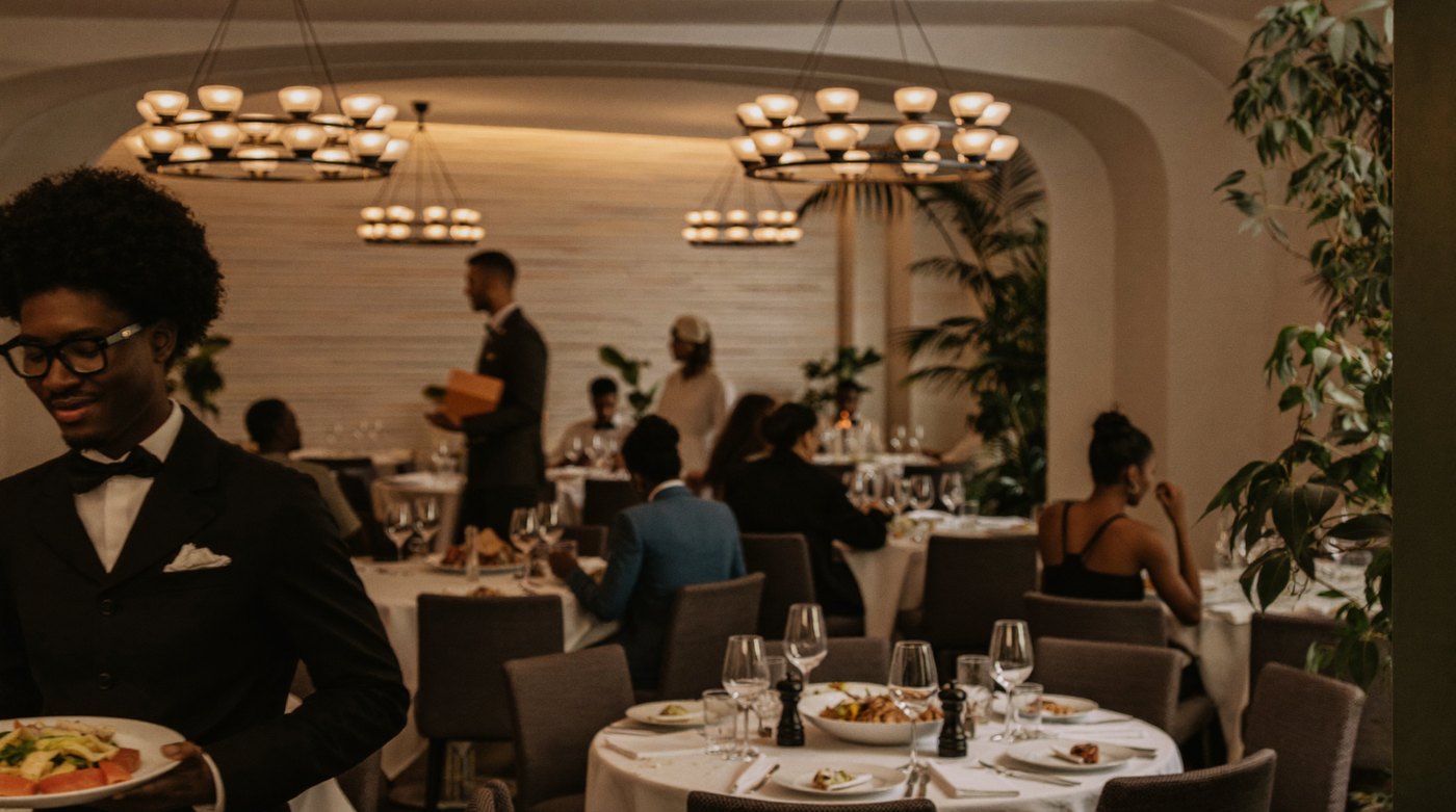 A waiter carrying a plate through a busy dining room